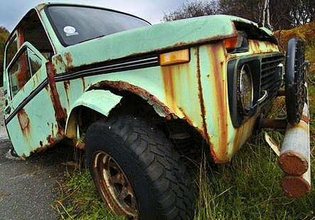 A rusty old Lada in a ditch, with the doors falling off and many parts missing