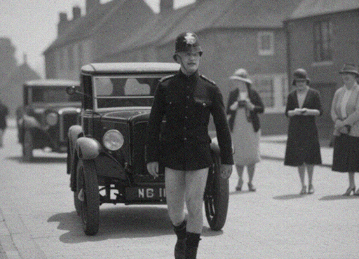 A black and white photograph of a policeman walking down a village street in the 1920s while three women look on